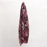 Pashmina rectangular con estampado botánico en tonos bordó, rosado y gris. Presenta bordes con desflecado suave.