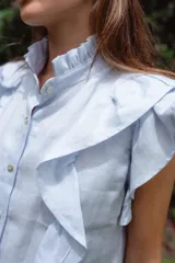 Vestido corto color verde oliva de lino con cuello mao fruncido, volados en los hombros, caída recta y botones al frente.