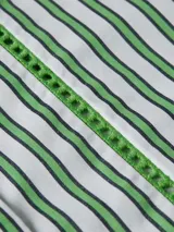 Camisa de corte amplio, a rayas verticales verdes y blancas, con cuello inglés, cierre frontal con botones y logo de Tommy Hilfiger bordado en el puño.