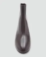 Botín de cuero vacuno color marrón oscuro con tacón bloque de 5,5 cm y cierre de cremallera en la parte posterior. Presenta punta redonda y diseño minimalista.