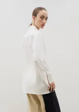 Camisa de corte holgado y diseño clásico, confeccionada en tela satinada con un sutil estampado floral tono sobre tono. Presenta cuello camisero, cierre frontal con botones y mangas largas con puños rectos.