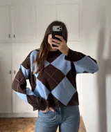 Sweater de punto con diseño de rombos en color marrón y celeste, cuello redondo y mangas largas.