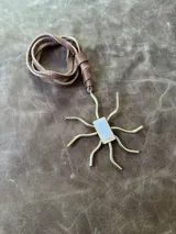 Collar con tiento de cuero marrón y dije con forma de sol en bronce y nácar.