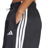 Pantalón de corte ancho y estilo urbano, confeccionado en tejido liviano color negro. Presenta cintura elástica con cordón ajustable, bolsillos laterales y las icónicas tres tiras de la marca en los costados, junto con el logo de Adidas bordado en la pierna.