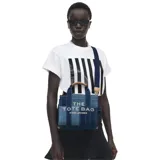 Cartera tipo tote bag de Marc Jacobs, confeccionada en denim con diseño de paneles en diferentes tonos de azul. Presenta el logo estampado en el frente, doble asa superior y correa de hombro ajustable y extraíble.