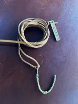 Collar de tiento de cuero tostado con dije en forma de letra en bronce y placa con la marca grabada.