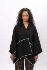 Ruana negra de corte asimétrico con detalles de costura a contraste en color blanco en los bordes. Confeccionada en tejido de algodón, presenta una caída fluida y diseño abierto.