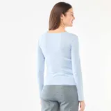 Camiseta de pijama de manga larga en color azul claro, confeccionada en tejido de punto calado con textura. Presenta un escote en V con una pequeña tapeta frontal decorada con botones.