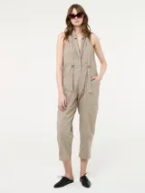 Mono color beige con bolsillos delanteros y tirantes ajustables.