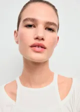 Camiseta de canalé color blanco, de manga larga y diseño entallado con cuello halter y detalles de aberturas.