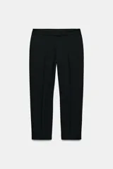 Pantalón de tiro alto color negro, con bolsillos delanteros y cierre frontal con cremallera y ganchos metálicos.