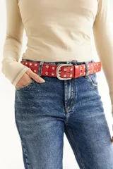 Cinturón rojo de cuero con tachas plateadas y hebilla metálica plateada.