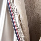 Campera de corte regular en color dorado metalizado, con cierre frontal, capucha y forro interior de piel sintética. Presenta bolsillos laterales abiertos y puños elásticos.