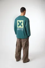 Remera de manga larga color verde, con cuello redondo y puños elásticos. Presenta un estampado gráfico en el pecho con el logo de la marca y caracteres japoneses en la manga izquierda.