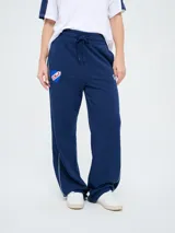 Pantalón de jogging azul marino con cordón ajustable en la cintura, bolsillos laterales y líneas blancas laterales. Presenta el escudo del Club Nacional de Football y el logo de Umbro bordados.