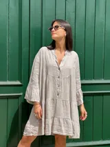 Vestido amplio de lino color verde lima, con cuello mao y abertura frontal con botones de coco. Presenta un diseño con canesú fruncido y volados en los puños de las mangas largas.