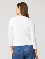 Cardigan blanco de tejido liviano con trama en relieve, cuello a la base y cierre frontal con botones a tono. Presenta mangas tres cuartos.