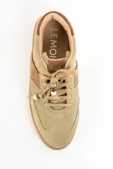 Zapatilla de gamuza en tono verde pistacho con detalles en cuero marrón, cordones al tono con cuentas decorativas y suela de goma color caramelo.