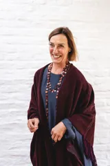 Ruana de lana color negro con terminación de flecos en los bordes y diseño con caída en picos en la espalda.