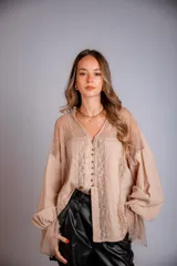 Camisa negra de manga larga con detalles de encaje en hombros y puños. Presenta un cuello tipo solapa y cierre frontal con botones dorados.