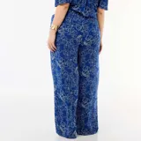 Pantalón ancho de punto crepé color azul con estampado floral en tono claro, de tiro alto y corte holgado.
