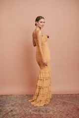 Vestido largo de fiesta color tostado, con escote en V, tirantes finos, cuerpo drapeado y falda sirena con múltiples volados en cascada.