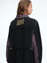 Vestido camisero de corte midi con diseño patchwork que combina paneles en tonos crudo y marrón con estampados florales sutiles. Presenta cierre frontal con botones, cuello camisero y mangas largas con puños.