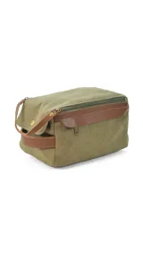 Neceser de diseño rectangular confeccionado en tela canvas color verde oliva con detalles en cuero sintético marrón. Cuenta con asa de mano lateral, cierre superior y bolsillo frontal con solapa.