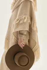 Ruana tejida en lana de cordero con diseño de sectores calados y terminación con flecos en los bordes.