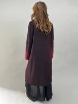 Tapado de paño de lana con diseño de solapas amplias, corte recto y bolsillos laterales ocultos. Presenta un degradado de color que va desde un tono bordó intenso en las solapas y puños hacia un tono más oscuro en el cuerpo.