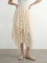Falda midi asimétrica de encaje color crudo, con diseño de capas superpuestas y cintura elastizada.
