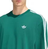 Remera de algodón color verde con diseño oversize, cuello redondo y mangas cortas. Presenta el logo Trefoil bordado en blanco en el pecho y las icónicas tres tiras de la marca en color blanco a lo largo de los hombros y mangas.