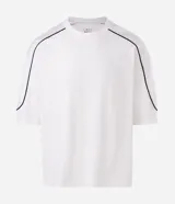Remera de algodón color blanco, con cuello redondo, manga corta y detalle de raya negra contrastante que recorre la parte superior de los hombros y mangas. Diseño de corte holgado.