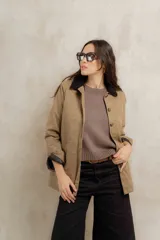Campera color beige con cuello de corderito negro, cierre frontal con botones y forro interior. Presenta un diseño de corte recto y mangas largas con puños vueltos.