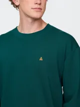 Remera de corte oversized en color beige claro, con cuello redondo y mangas de largo medio. Presenta un pequeño bordado del oso Brannan de Gap en el lado izquierdo del pecho.