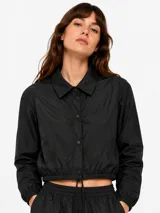 Campera corta negra de nylon, con cuello camisero, cierre frontal de botones a presión, mangas largas con puños elásticos y ruedo ajustable con cordón.