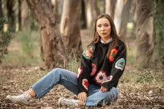 Sweater negro de lana con cuello redondo y apliques de flores de crochet multicolores.