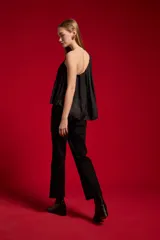 Blusa de poliéster color negro, con diseño asimétrico de un solo hombro, plisado ligero y corte holgado.
