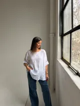 Blusa de lino color blanco, de corte amplio, con escote redondo y mangas tres cuartos con presillas para arremangar.