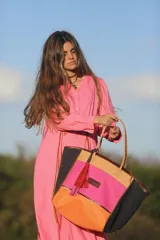 Bolso de fin de semana estilo tote de lona con estampado camuflado, detalles en cuero marrón y gamuza azul, manijas largas y borla decorativa colgante.