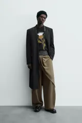 Levita negra de corte relajado confeccionada en tejido con lana. Presenta cuello sin solapa, mangas largas con puños abotonados, bolsillo de vivo en el pecho y bolsillos con solapa en la cadera. Incluye bolsillos interiores, abertura en el centro de la espalda y cierre frontal con botonadura.