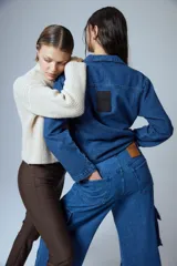 Pantalón tipo cargo de jean azul con corte oversize y tiro medio. Presenta múltiples bolsillos laterales y delanteros con solapa, confeccionado en algodón.
