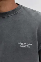 Buzo de cuello redondo en color gris oscuro con efecto lavado, manga larga y calce holgado. Presenta una pequeña estampa minimalista en el pecho.