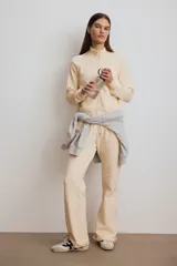 Campera deportiva de felpa de algodón color beige, de corte ajustado, con cuello elevado, cierre frontal y bolsillos laterales discretos. Presenta puños y bajo acanalados.