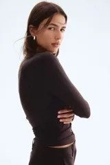 Top de manga larga color marrón oscuro (casi negro), ajustado al cuerpo, con escote redondo y detalle de frunces centrales y laterales que crean un efecto drapeado.