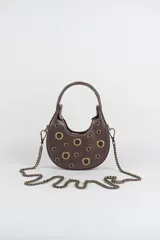 Cartera hobo mini de cuero marrón, con forma semicircular estructurada, decorada con arandelas metálicas doradas distribuidas en el frente. Cuenta con una manija corta superior y una correa de cadena metálica larga y desmontable.