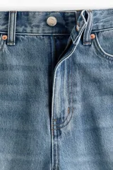 Jean de cinco bolsillos en denim de algodón rígido, de diseño curvo con volumen y corte holgado de cadera a muslo, algo más ceñidas en el bajo. Cintura clásica con cierre y botón.