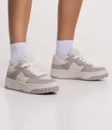 Championes de caña corta marca Satinato, confeccionados en material sintético tipo cuero (PU). Presentan un diseño de paneles en tonos beige y tostado, con suela de plataforma tipo caja y cierre mediante cordones.