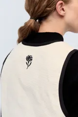 Chaleco negro de pana con bordes color beige y lazos de ajuste frontales.