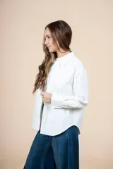 Camisa blanca de corte clásico con bolsillo en el pecho, mangas largas y botones al tono.